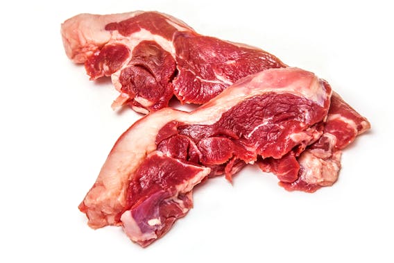 Uncooked goat meat leg steaks isolated on a white studio background.
